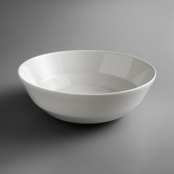 A white Schonwald Allure round porcelain salad bowl on a grey surface.