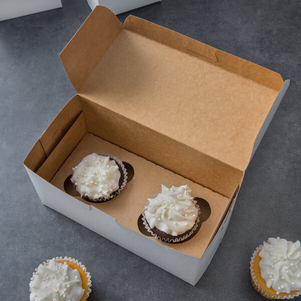 A white cupcake box with two cupcakes and white frosting on top.