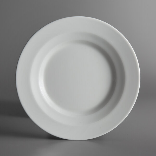 A Schonwald bone white porcelain plate with a rim on a gray surface.