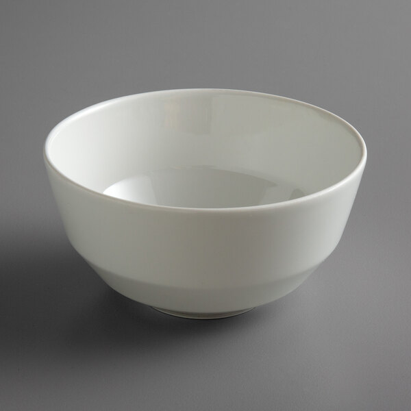 A Schonwald bone white porcelain bowl on a gray surface.