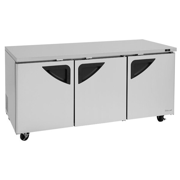 A stainless steel Turbo Air undercounter refrigerator with black handles on wheels.