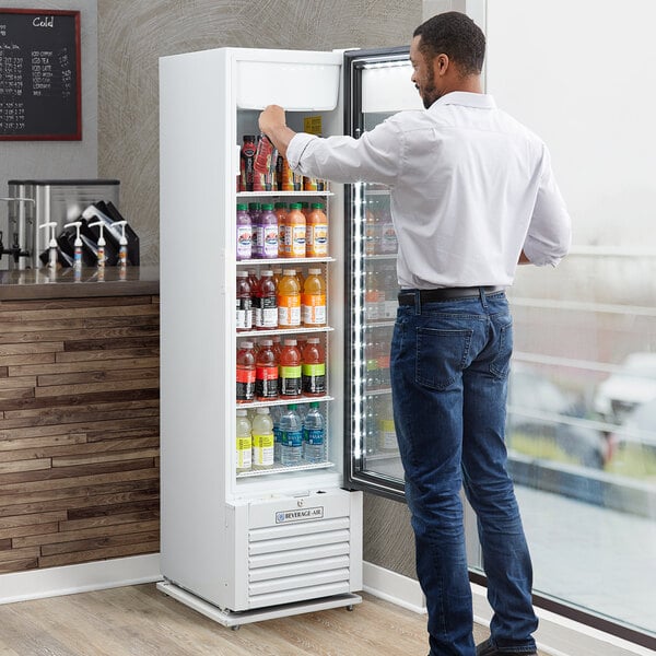 A man in a white shirt opening the white Beverage-Air Marketeer Series refrigerator full of drinks.
