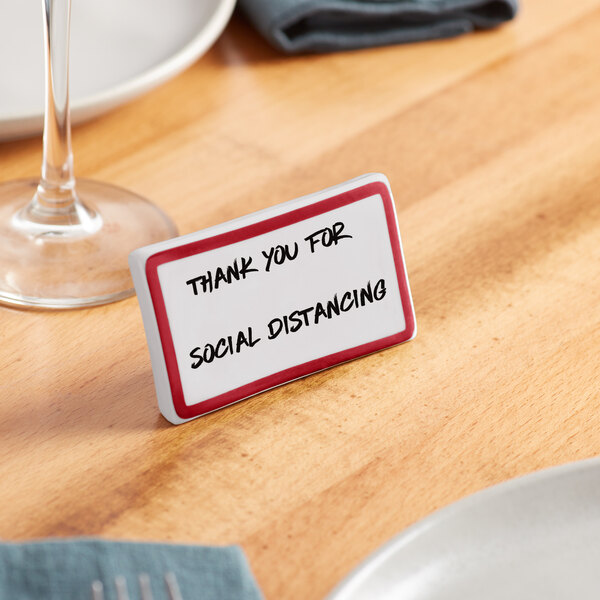A maroon ceramic table tent sign with a decal border on a table.