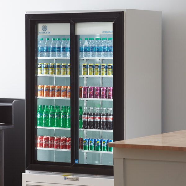 A Beverage-Air white refrigerated sliding glass door merchandiser full of soda and water bottles.