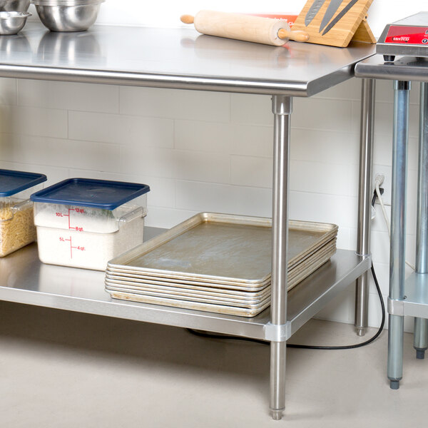 A metal Advance Tabco stainless steel work table with pans and bowls on an undershelf.