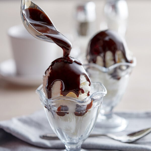 A glass cup with a scoop of J. Hungerford Smith chocolate sauce on top of ice cream.