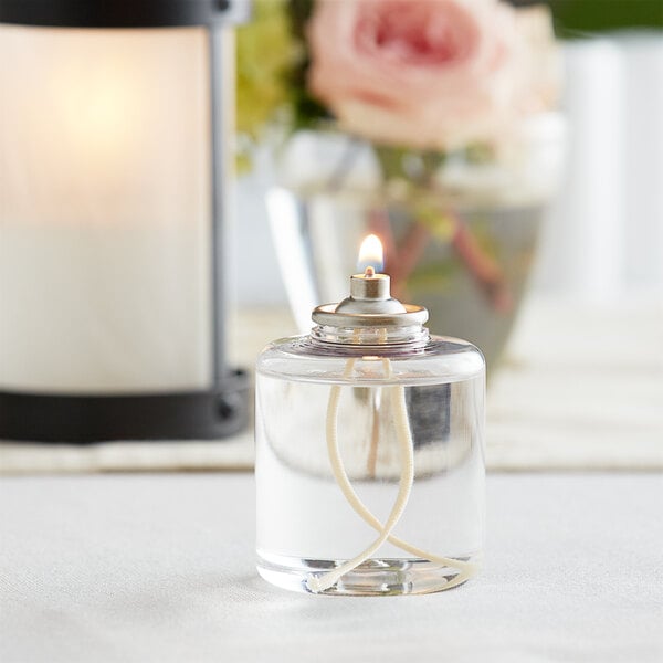 A Leola liquid wax paraffin fuel candle in a glass container with a flame on top.
