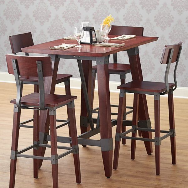 A Lancaster Table & Seating mahogany wood table top on a table with chairs and glasses.