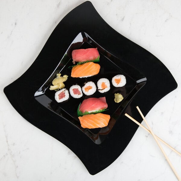 A Fineline black plastic square plate with sushi and chopsticks on it.