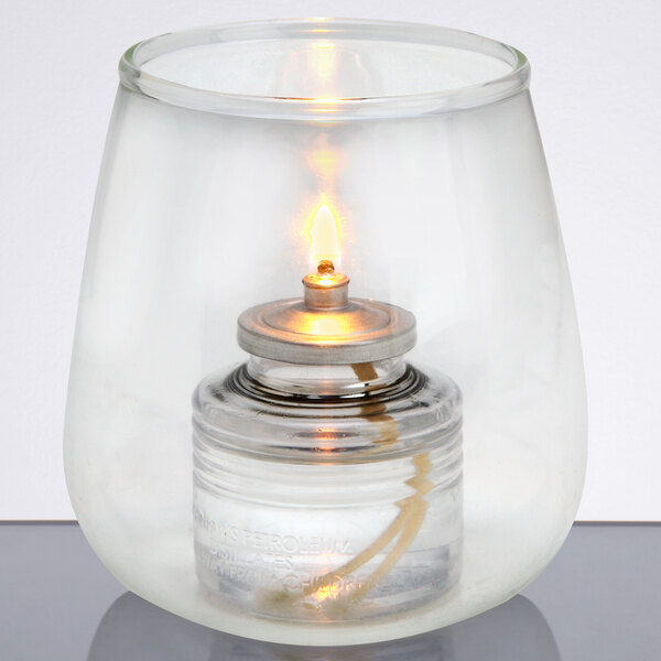 A Sterno glass candle holder with a flame inside.