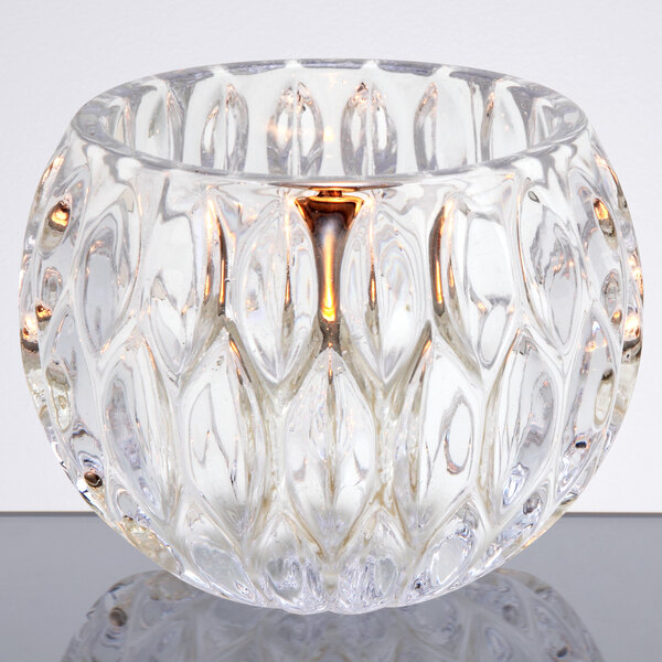 A Sterno Iris votive glass candle holder on a table.