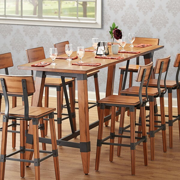 A Lancaster Table & Seating wooden table top with chairs and wine glasses.