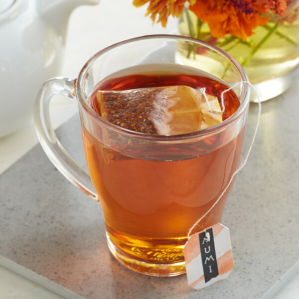A glass cup of Numi Organic Rooibos tea with a tea bag in it.