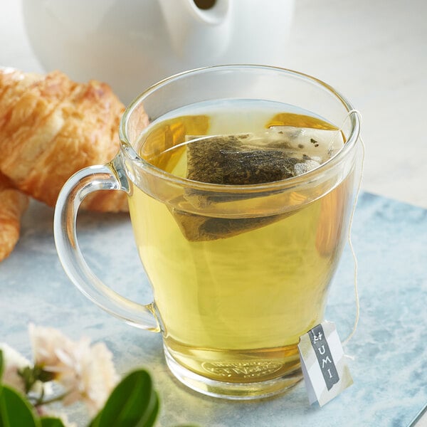 A glass mug of Numi Organic Gunpowder Green Tea with a tea bag in it.
