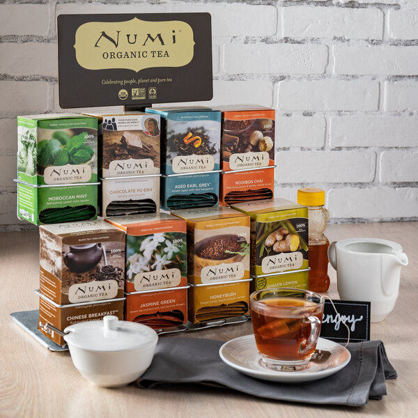 A Numi tea display rack holding boxes of tea on a table in an organic food store.