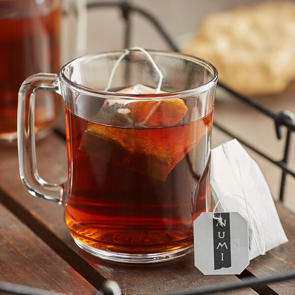 A glass mug of Numi Organic Emperor's Pu-Erh tea with a tea bag.