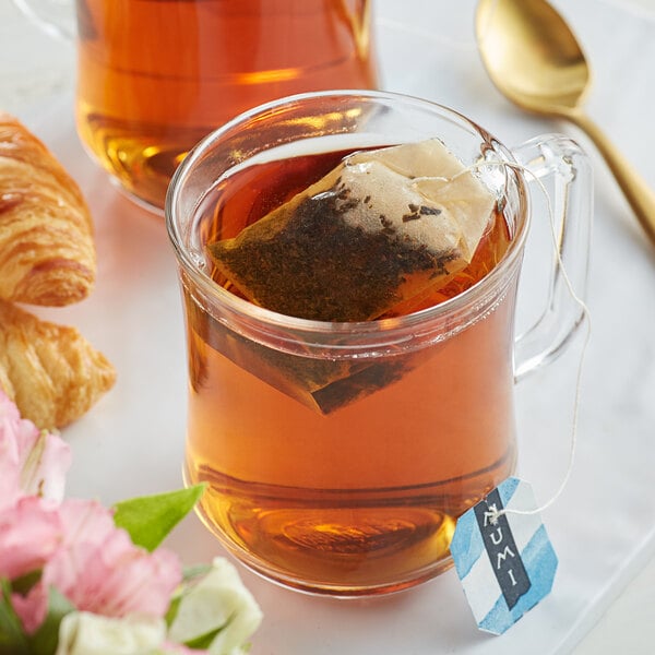 A glass mug of Numi Organic Aged Earl Grey Tea with a tea bag in it.