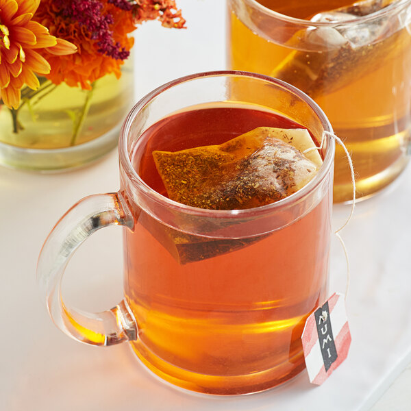 A glass mug of Numi Organic Rooibos Chai Tea with a tea bag in it.