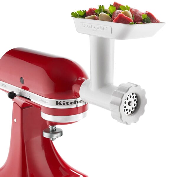 A red KitchenAid food grinder attachment on a white background with a bowl of meat.