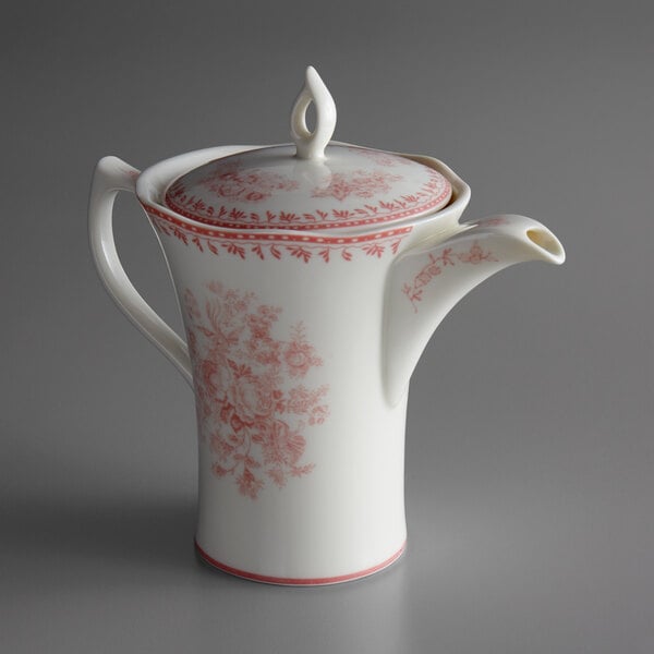 A white porcelain teapot with a pink floral design and a lid.