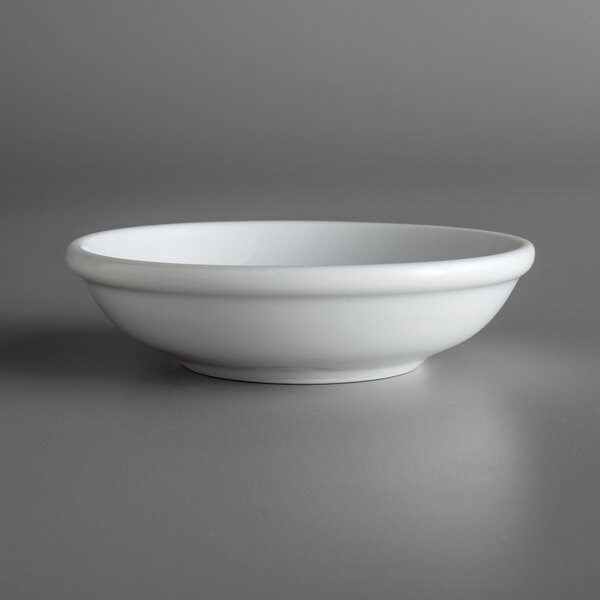A Oneida Fusion bright white porcelain sauce dish on a table.