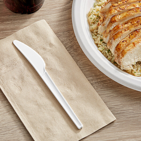 A plate of food with a white EcoChoice compostable plastic knife on a table.