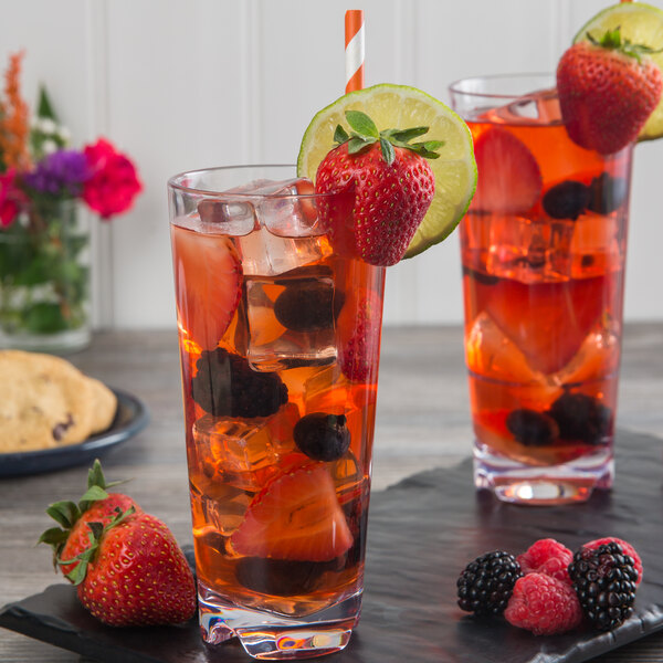 Two Libbey Tritan plastic beverage glasses with fruit juice and fruit slices on a black tray.