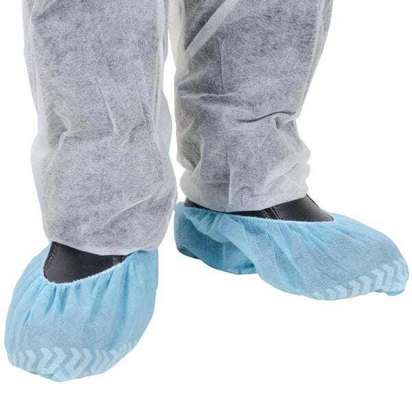 A person wearing blue Cordova shoe covers over shoes.
