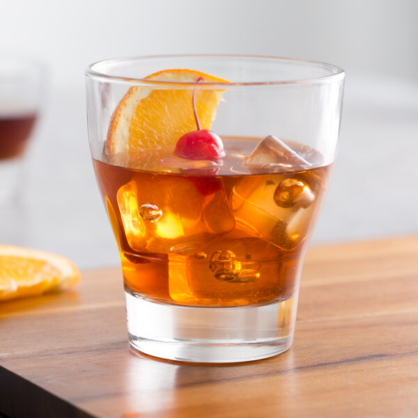 An Arcoroc Urbane double old fashioned glass with a drink and ice cubes and a slice of orange.