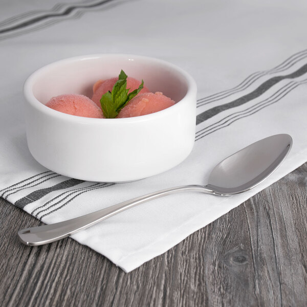 A bowl of pink ice cream with a Oneida Baguette stainless steel oval bowl spoon on a napkin.