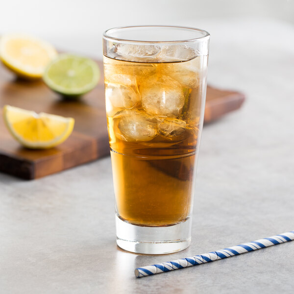 A stackable beverage glass of iced tea with ice and lemons on a white background.