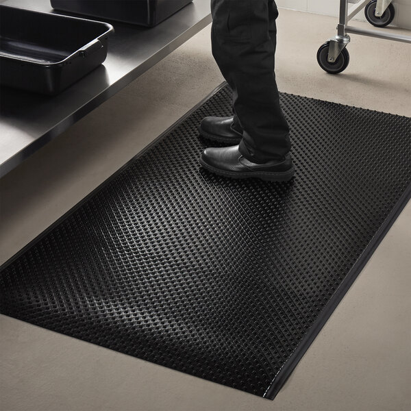 A person standing on a black ES Robbins Feel Good anti-fatigue floor mat.