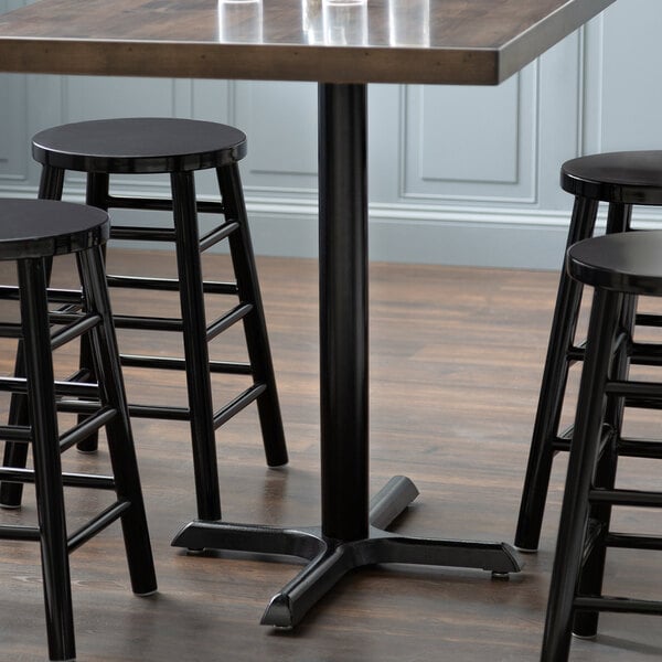 A Lancaster Table & Seating black cast iron counter height table base with three stools around it.