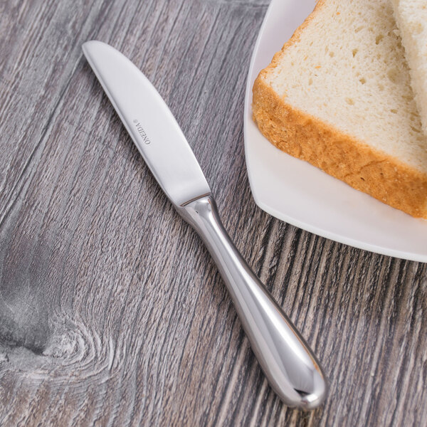 A plate of bread and a Oneida Baguette stainless steel butter knife.