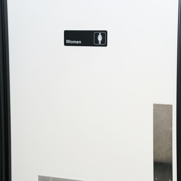 A white door with a black and white Thunder Group Women's Restroom sign.
