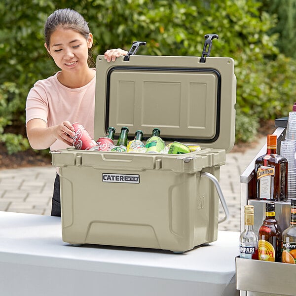 A woman opening a CaterGator outdoor cooler to put cans inside.
