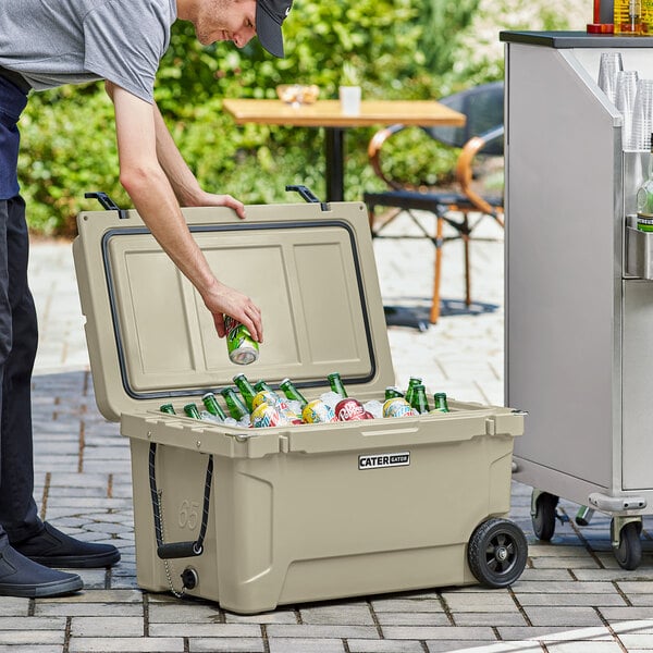 A man putting a can into a CaterGator outdoor cooler with drinks.