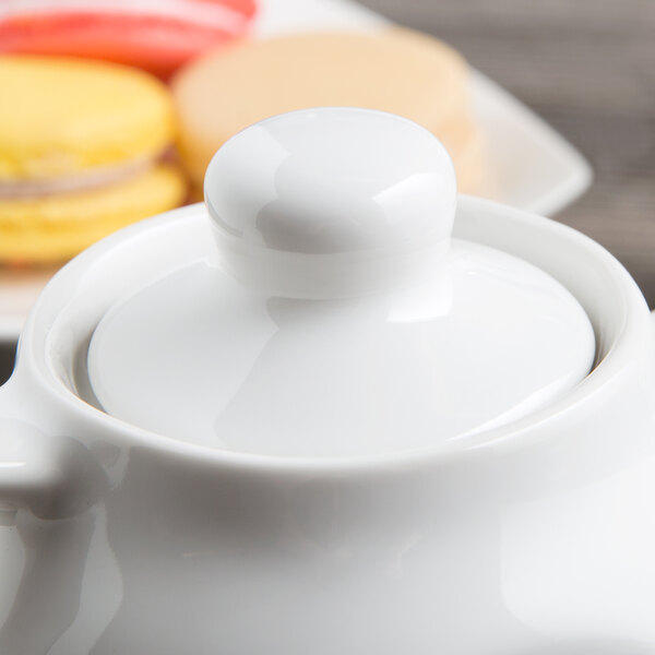 A white Tuxton china teapot with a lid.