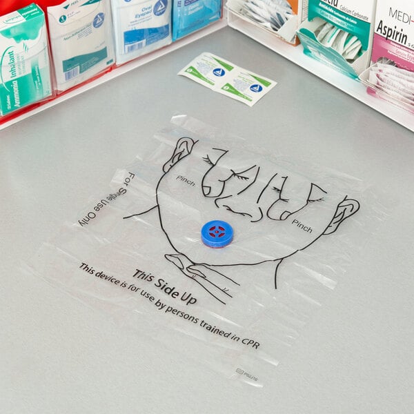 A Medi-First CPR mask on a table with medical supplies.