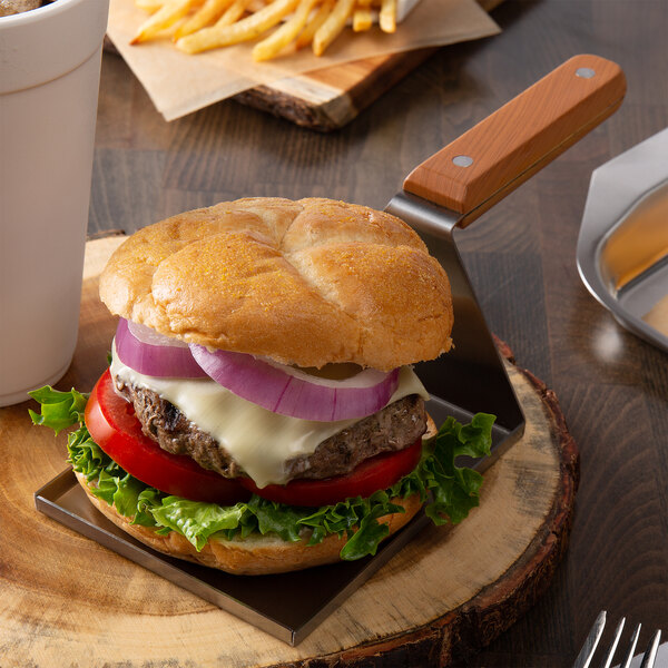 A Tablecraft stainless steel spatula server serving a burger with lettuce and onion.