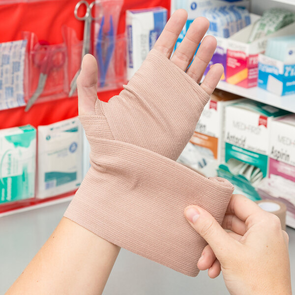 A hand using a Medi-First elastic bandage with clips to wrap a finger.