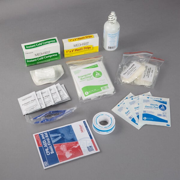 A Medique small vehicle first aid kit on a table with various first aid items.