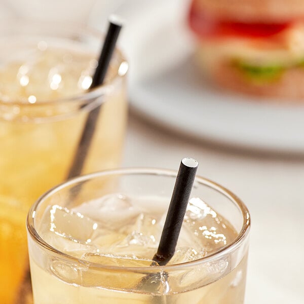A glass of iced tea with ice and an EcoChoice black paper sip straw.