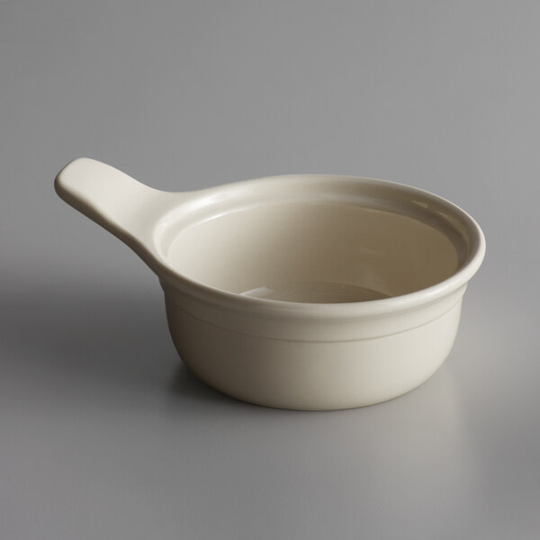 A close-up of a white porcelain casserole dish with a handle.