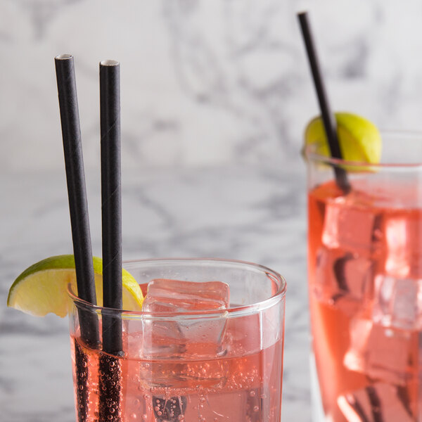 Two glasses of pink drink with black EcoChoice paper straws on a table.