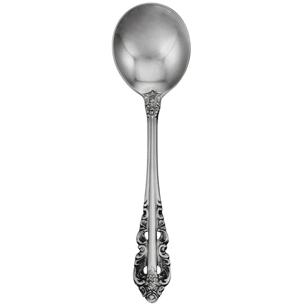 A close-up of a Walco stainless steel bouillon spoon with an ornate design.