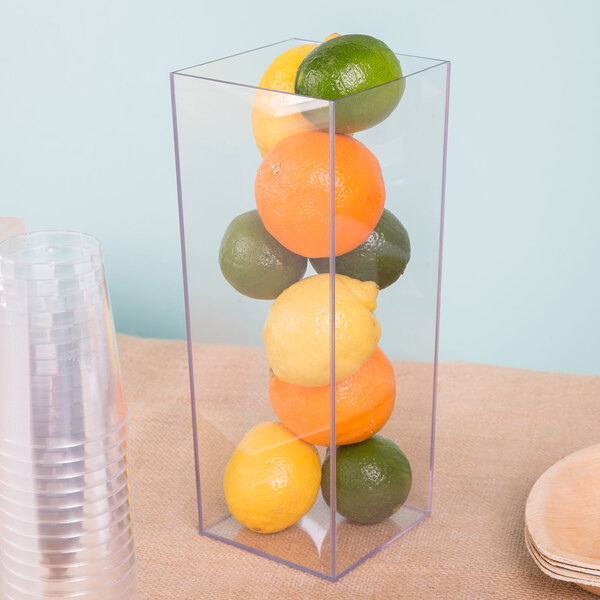 A Cal-Mil clear acrylic square accent vase with lemons, limes, and oranges inside.