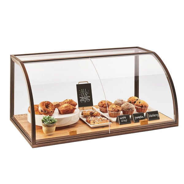 A Cal-Mil Sierra bakery display case with pastries on a wood base.