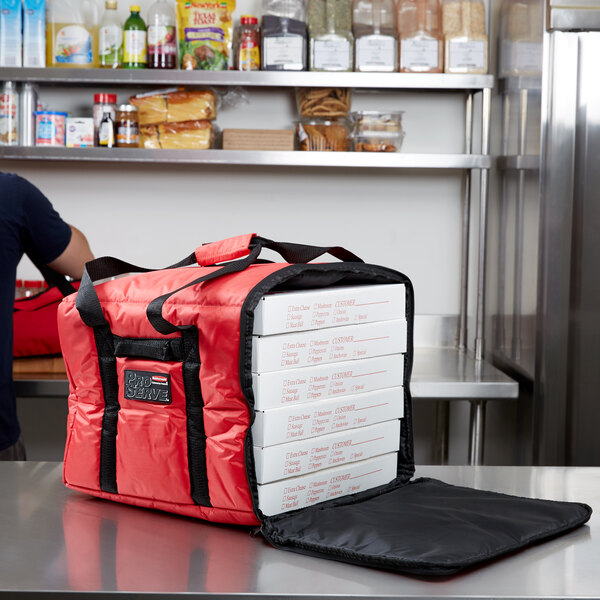 A man standing in front of a large red and black Rubbermaid ProServe pizza bag with stacked pizza boxes inside.