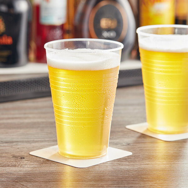 Two Choice translucent plastic cups filled with beer sit on a table.
